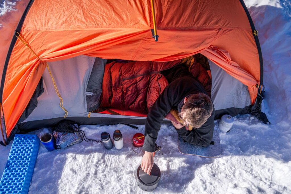 camper bereitet warmes essen vor zelt im schnee zu als alternative zur petroleum heizung camping