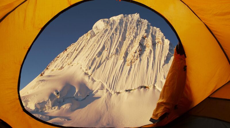 blick aus gelbem zelt auf schneebedeckten gipfel im winter bei campingtour mit petroleum heizung camping