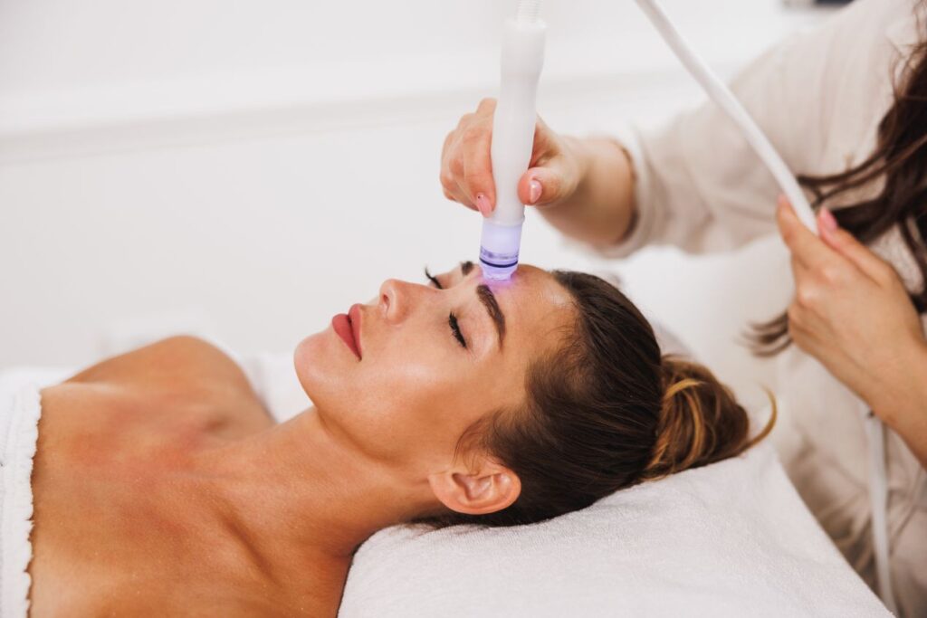 Frau bei Hydrafacial Behandlung im Kosmetikstudio, moderne Gesichtsbehandlung mit Tiefenreinigung